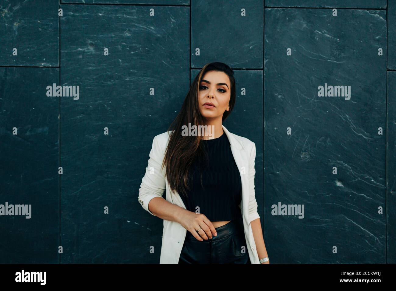Portrait of young woman in front of black wall Stock Photo - Alamy