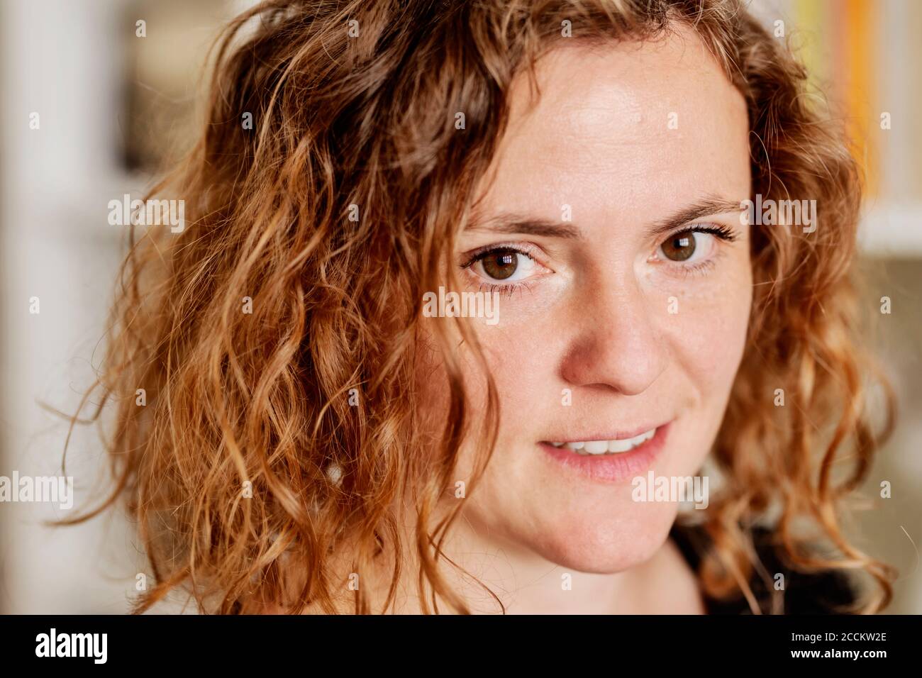 Close-up portrait of mid adult woman with wavy hair at home Stock Photo