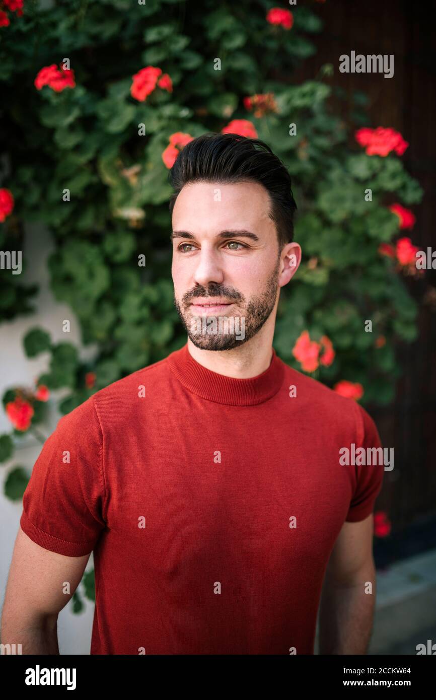 Smiling man standing against flowering plant outdoors Stock Photo