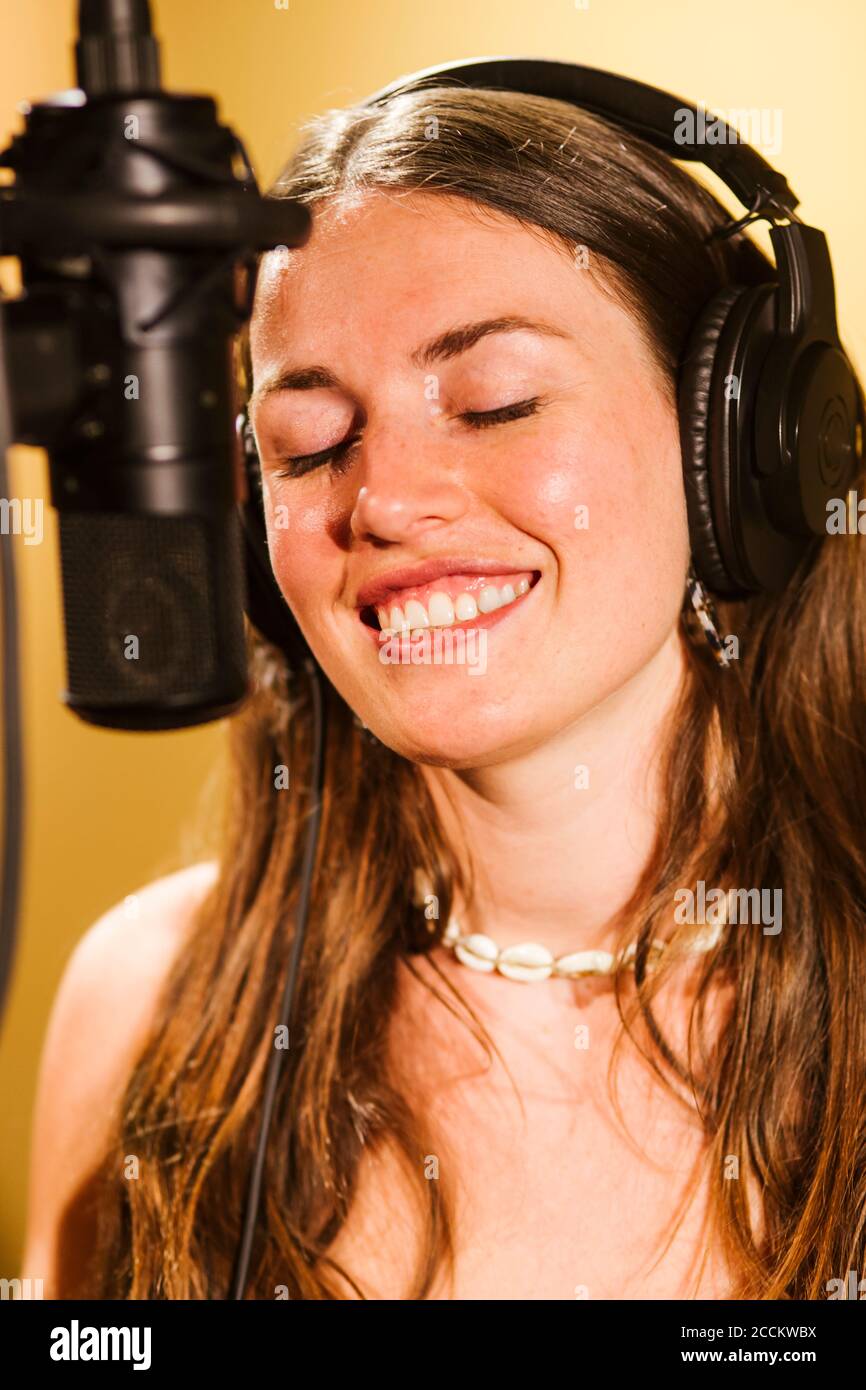 Singer with headphones at microphone in recording studio Stock Photo