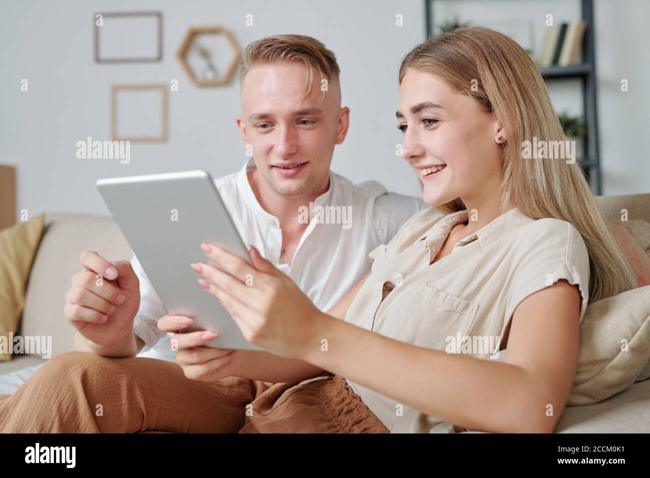 Contemporary young affectionate couple using tablet to watch online video Stock Photo