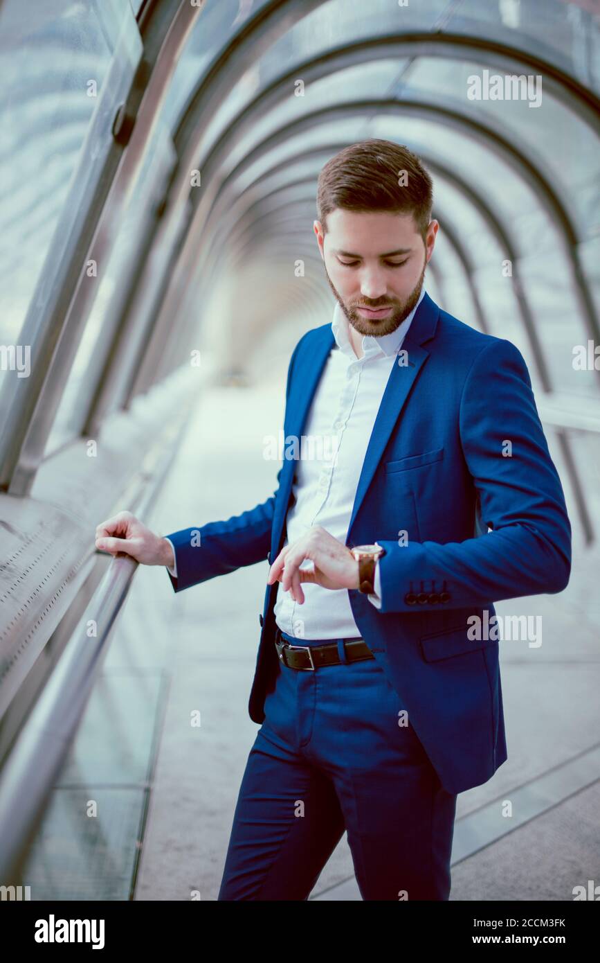 Young businessman in a blue suit checking the time Stock Photo - Alamy