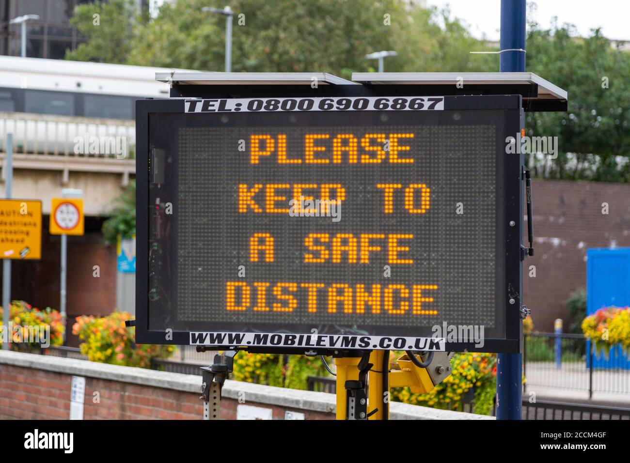 An electronic signboard outside a train station stating please keep a safe distance during the coronavirus pandemic Stock Photo
