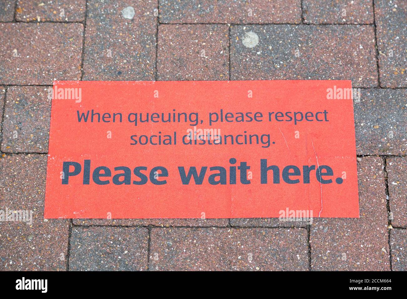 A sign on the ground outside a supermarket showing customers where to queue to conform to social distancing guidelines Stock Photo