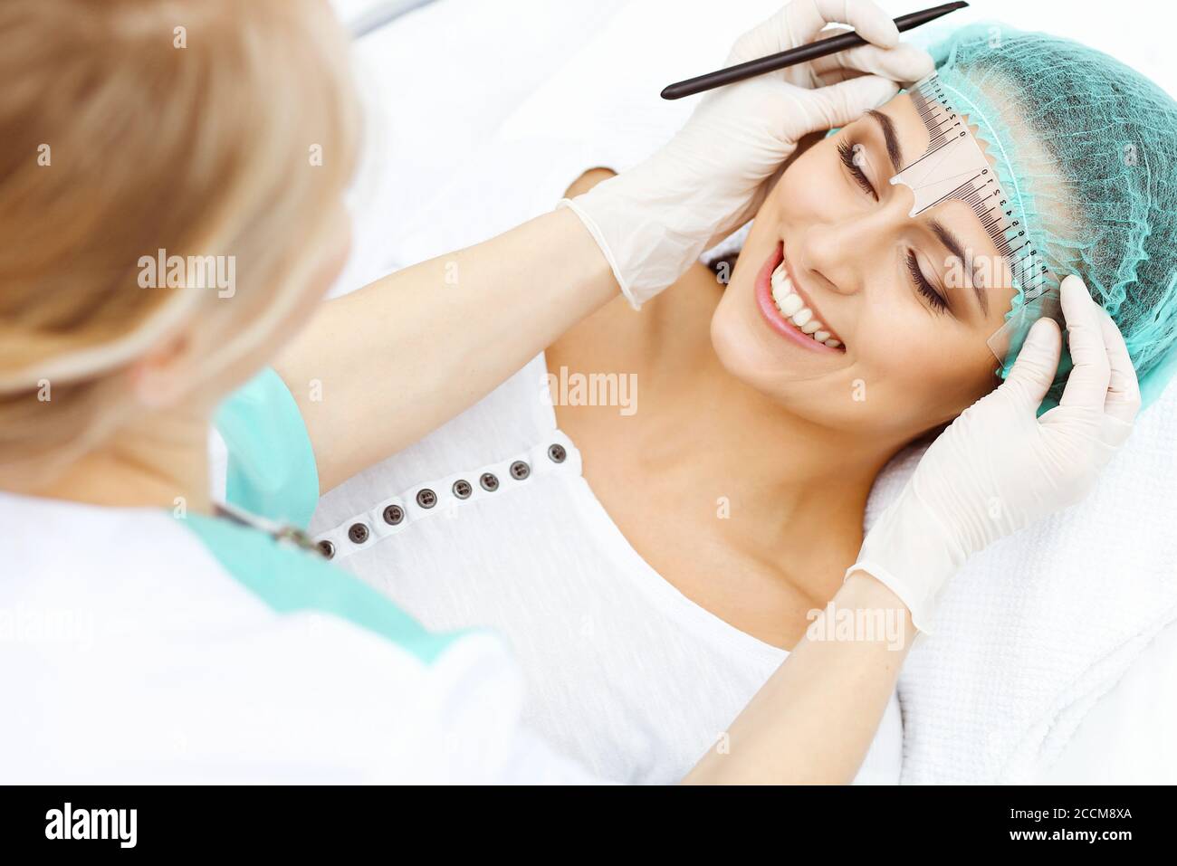 Professional beautician is going to correct eyebrow line at woman face ...
