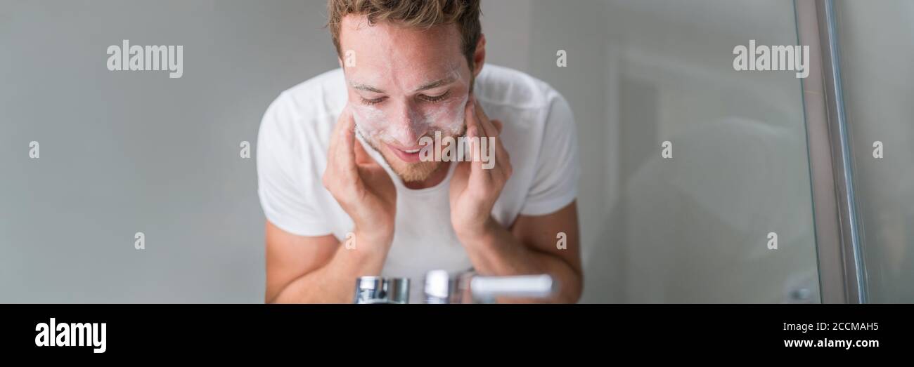 Man washing face banner panorama. Person cleansing with facial cleanser face wash soap in bathroom sink at home Stock Photo