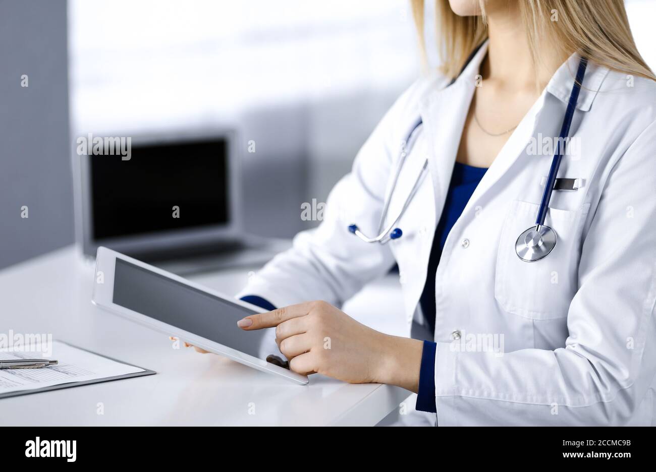 Unknown Young Woman Doctor Is Checking Some Medication Names While Sitting At The Desk In Her Cabinet In A Clinic Physician With A Stethoscope Is Stock Photo Alamy
