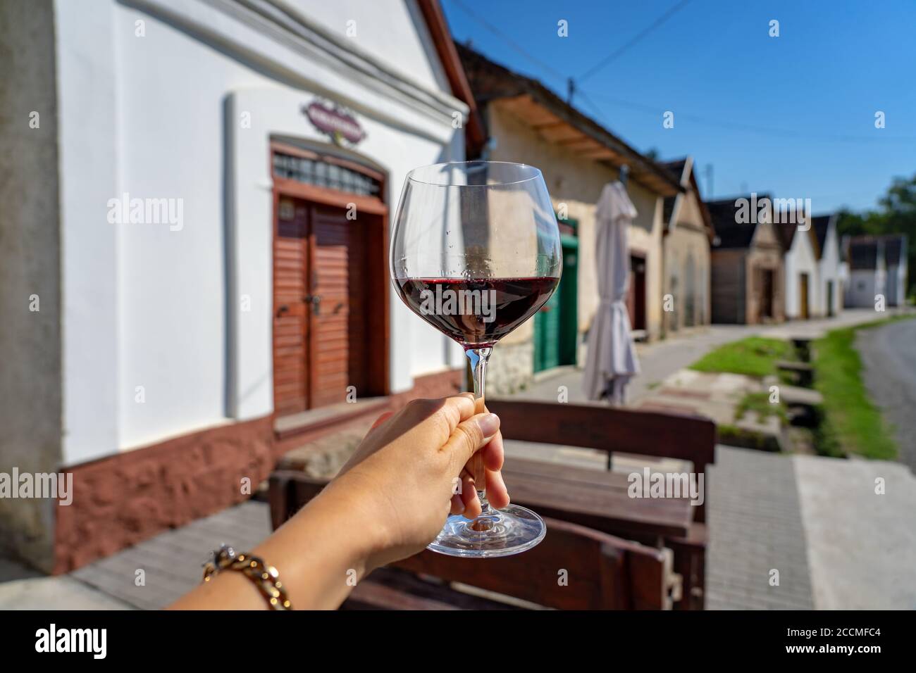Glass of red wine with many colorful old traditional wine cellers in