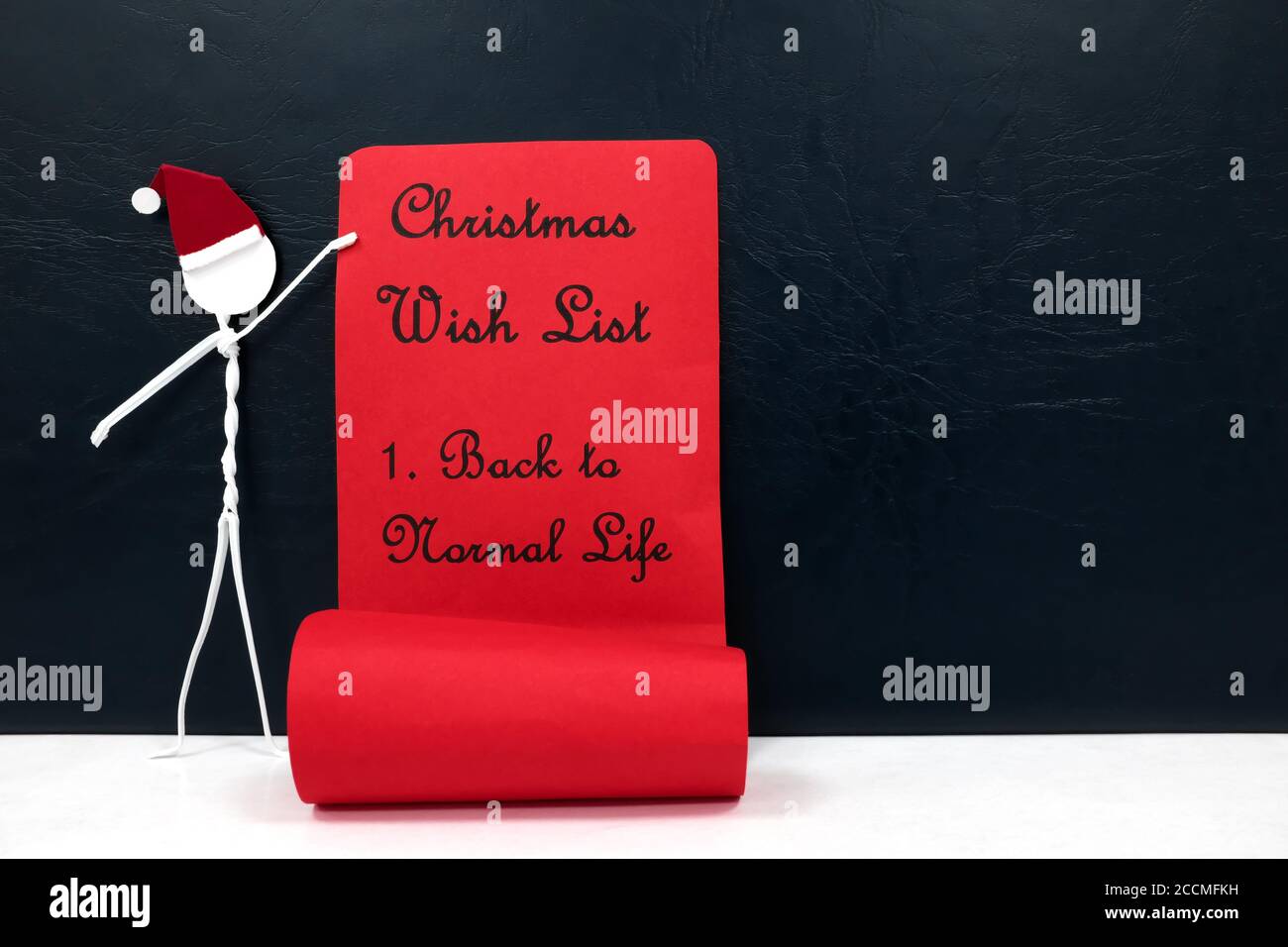 Stick man figure holding a red paper roll with christmas wish list. Back to normal life from covid concept. Stock Photo