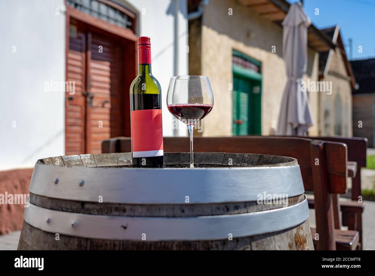 glass of red wine with bottle on a barrel with many colorful old