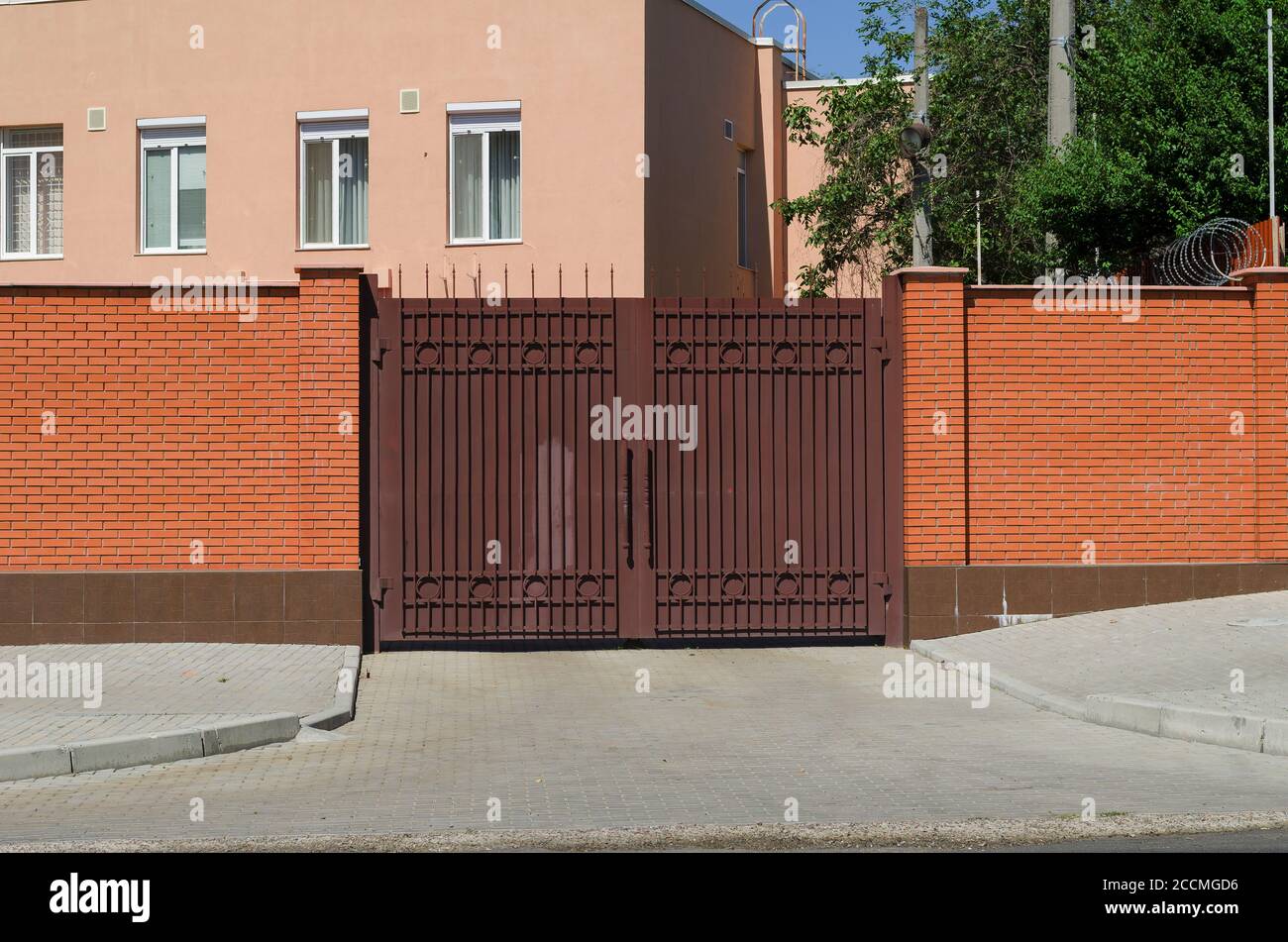 High brick fence and closed metal gates. A twostory office building in