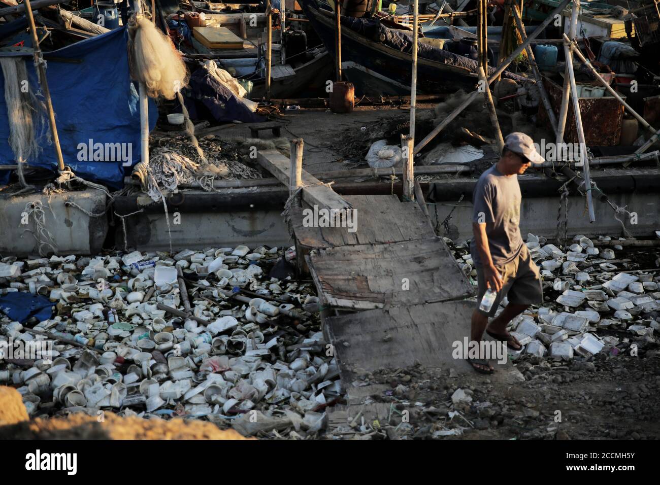 Jakarta, DKI Jakarta, Indonesia. 22nd Aug, 2020. A man walks trough a pile of garbage.Plastic waste that has accumulated around the coast endangers marine life and local residents. Credit: Aslam Iqbal/SOPA Images/ZUMA Wire/Alamy Live News Stock Photo