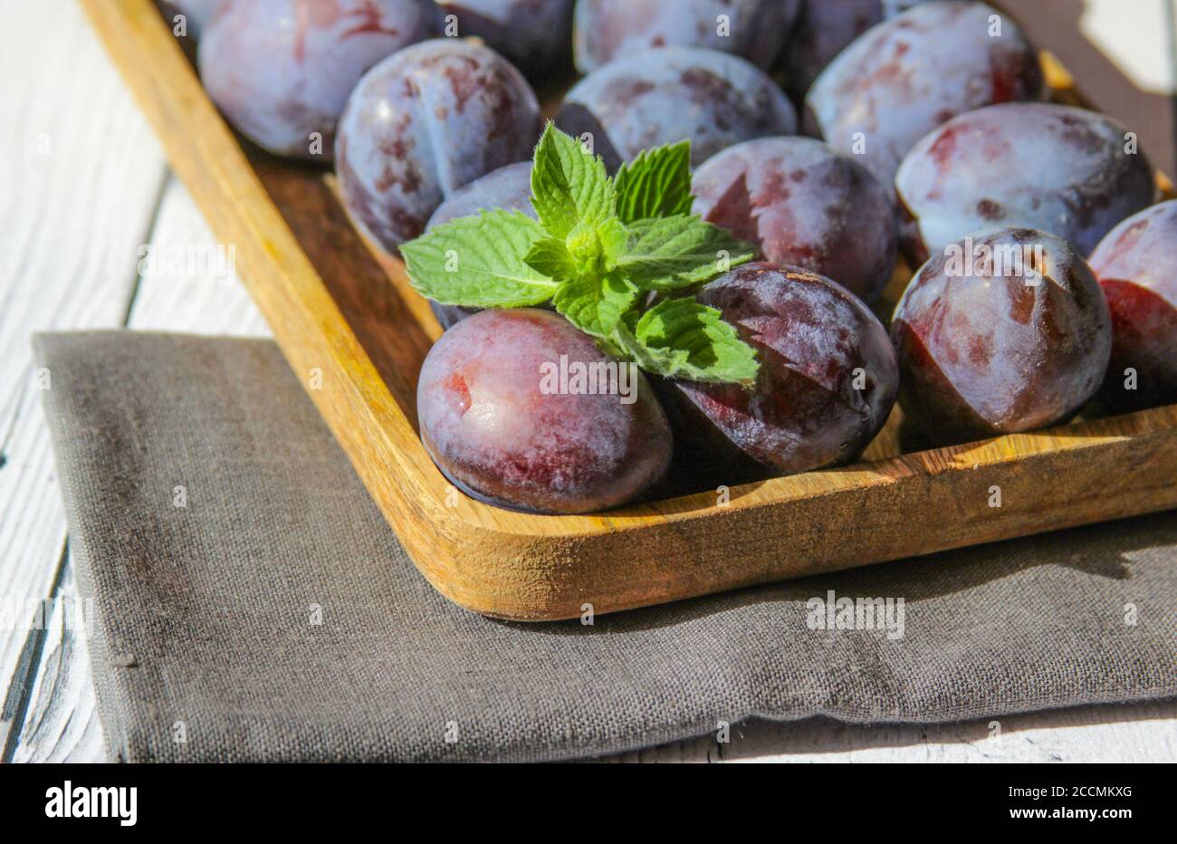 Fresh and sweet plum with leaves on the wooden background. Stock Photo