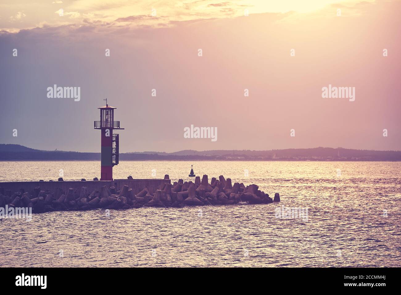 Pier with lighthouse at sunset, color toning applied, Swinoujscie, Poland. Stock Photo