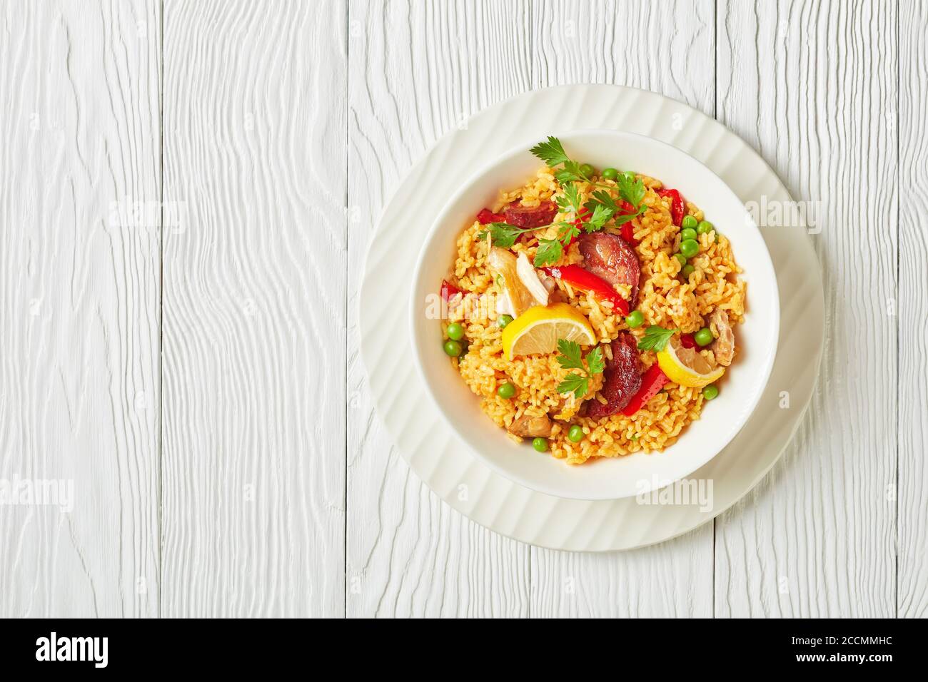 portion of spanish chicken paella with valencian bomba rice, chicken thigh  meat, chorizo sausages, vegetables and spices served on a white plate on a  Stock Photo - Alamy