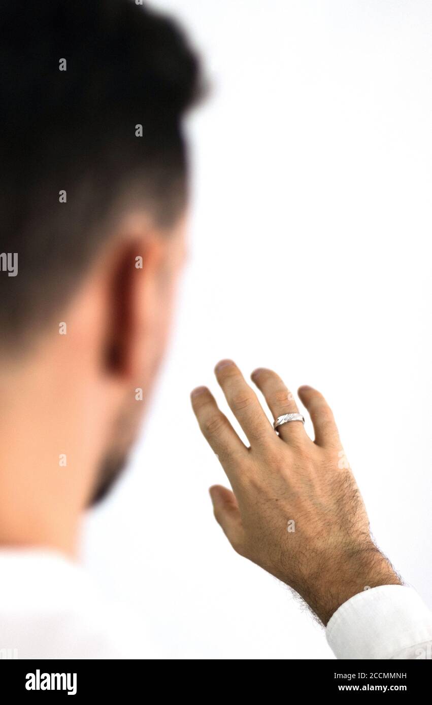 White man looks at his hand with a ring placed on his finger. Jewelry for men. Engagement ring