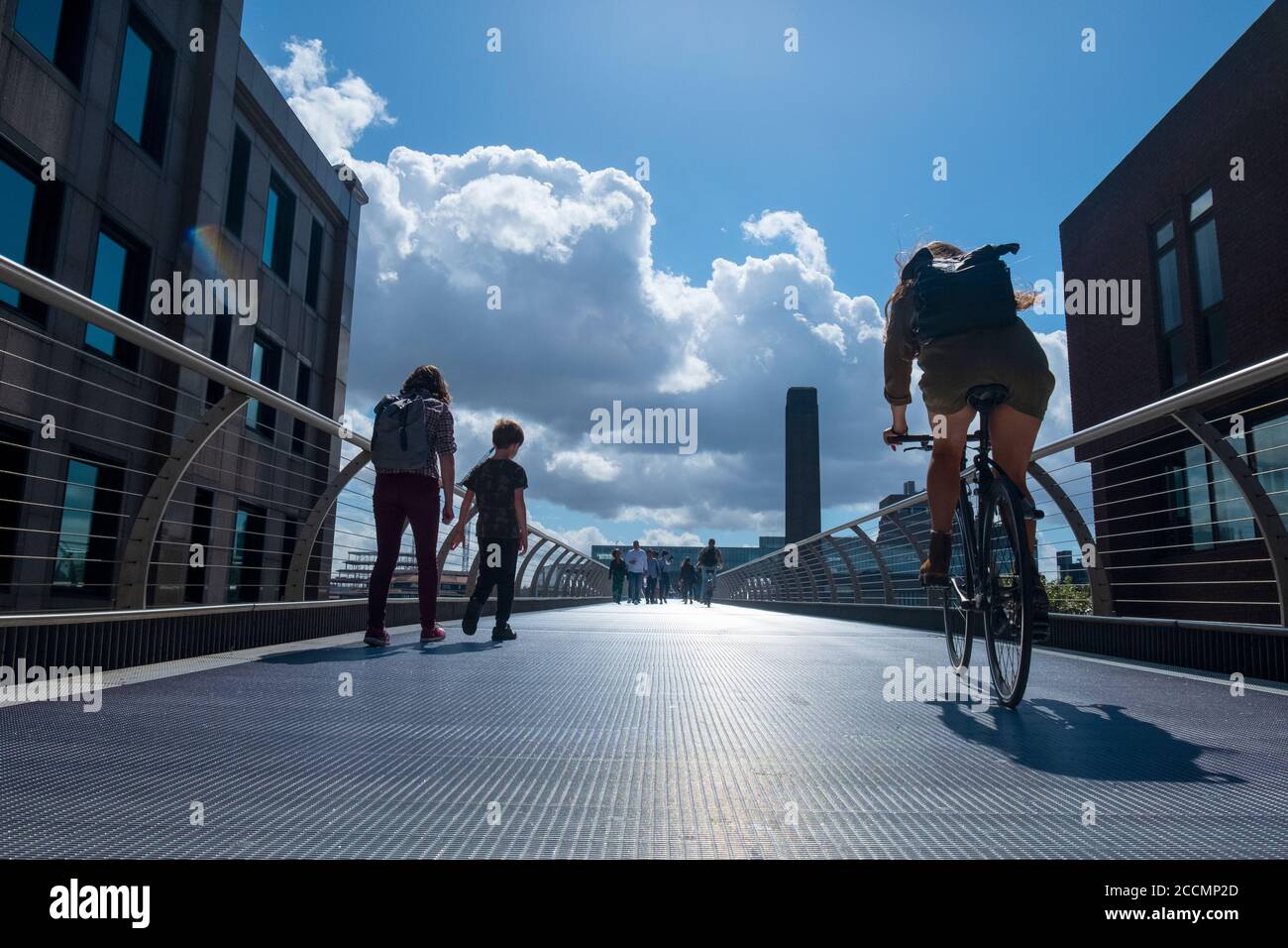People walk and cycle across the Millennium Bridge, the famous wobbly footbridge crossing the Thames from St Pauls to the Tate Modern in London Stock Photo