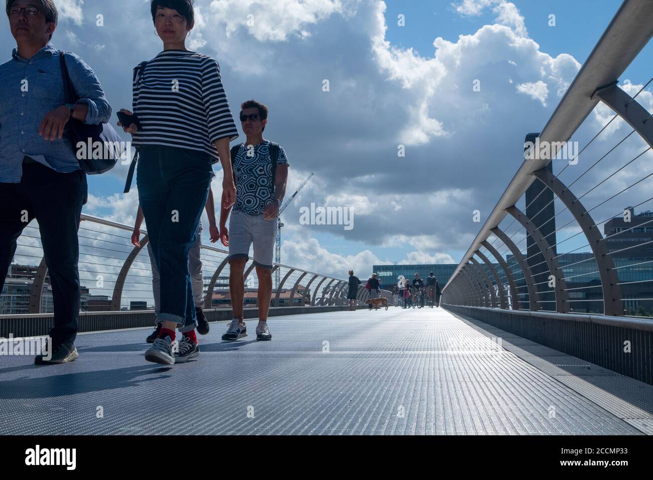 People walk and cycle across the Millennium Bridge, the famous wobbly footbridge crossing the Thames from St Pauls to the Tate Modern in London Stock Photo