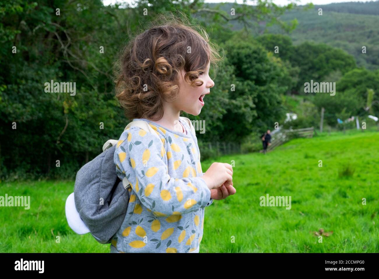 Happy excited girl 3 years standing shouting in field in the countryside on holiday staycation in late summer during pandemic Britain UK  KATHY DEWITT Stock Photo