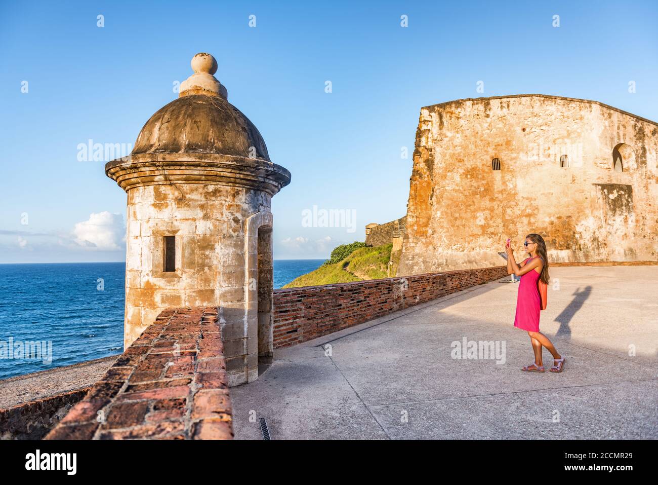 Old San Juan city tourist taking photo in Puerto Rico. Woman using phone taking pictures of ruins of watch tower of San Cristobal Castillo Fort, with Stock Photo