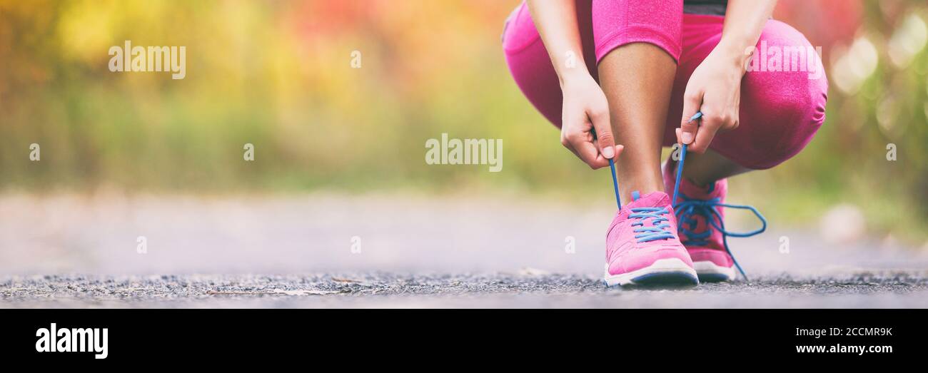 Running shoes runner woman tying laces for autumn run in forest park panoramic banner copy space