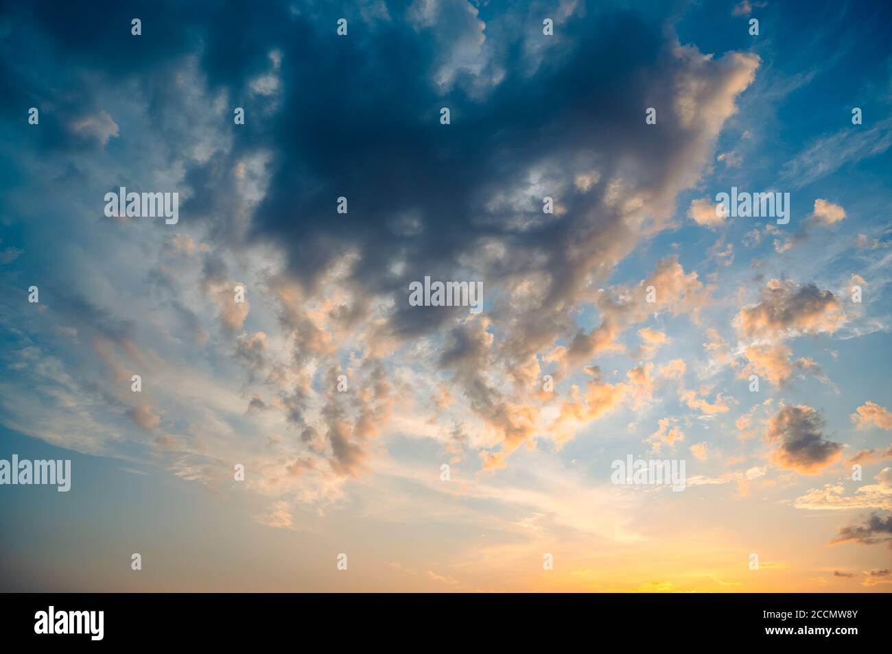 Beautiful summer sky full of clouds at sunset at golden hour. Interesting warm colors on the horizon. Stock Photo