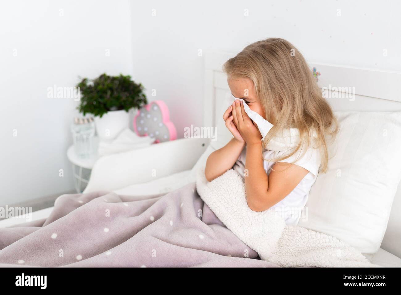 Toddler girl is lying in bed. The child is cold and sick and has a