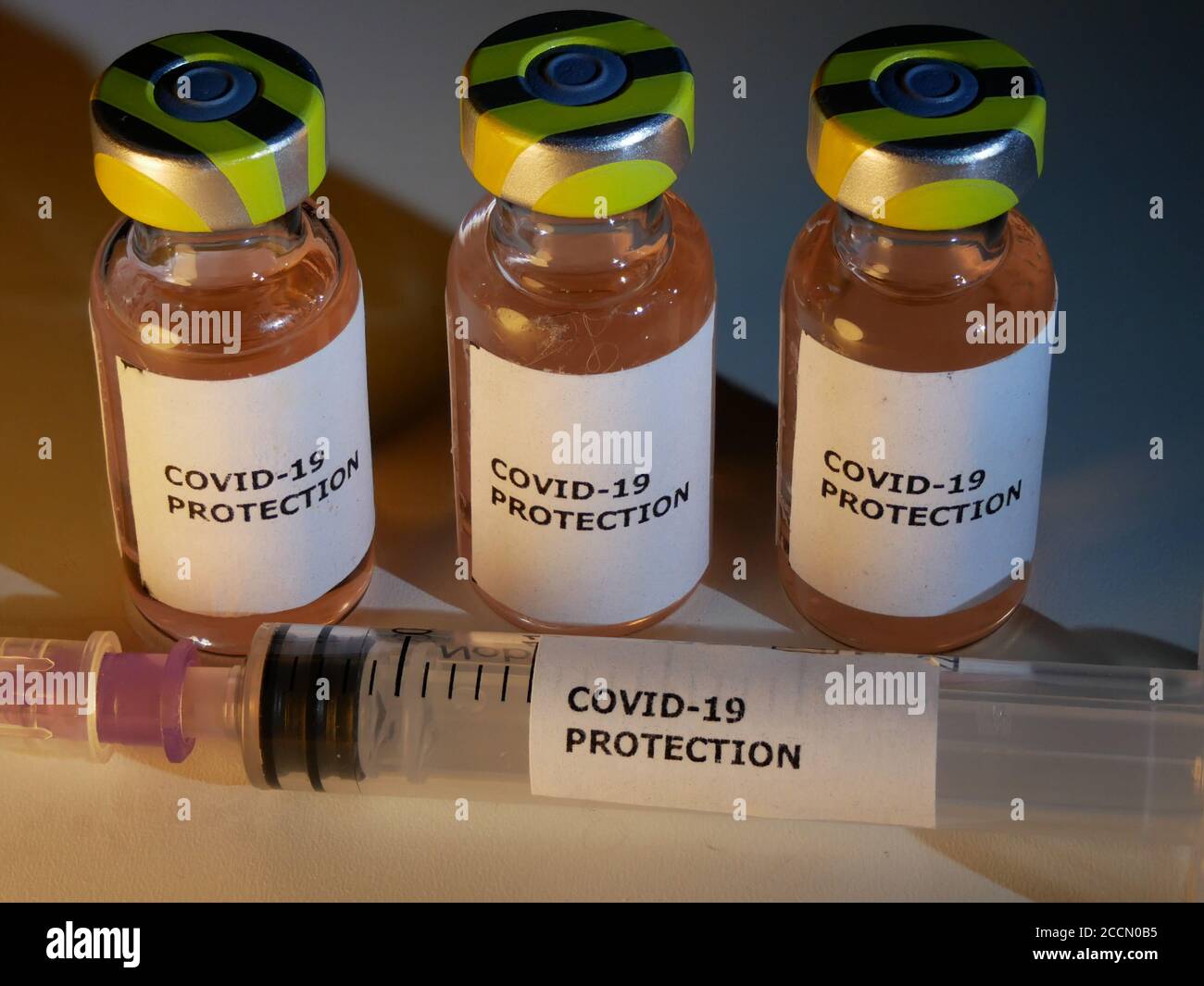Vials of vaccine against covid-19 with injection needle and protection against coronavirus label in close up Stock Photo