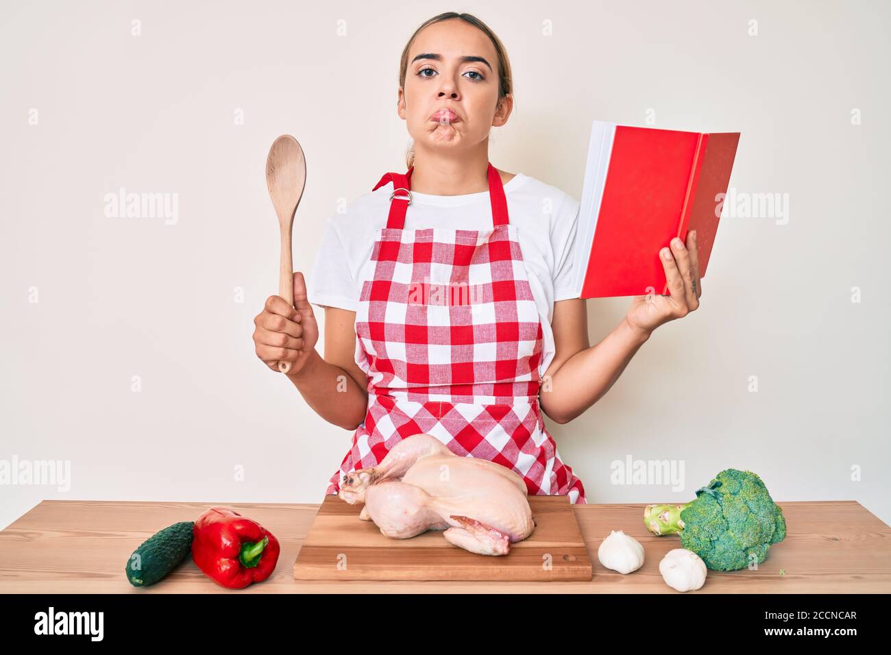 Young beautiful blonde woman wearing professional baker apron reading ...