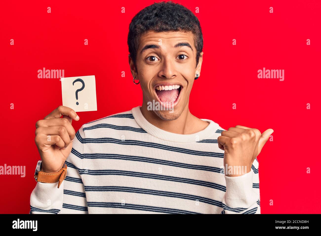 Young african amercian man holding question mark reminder pointing ...