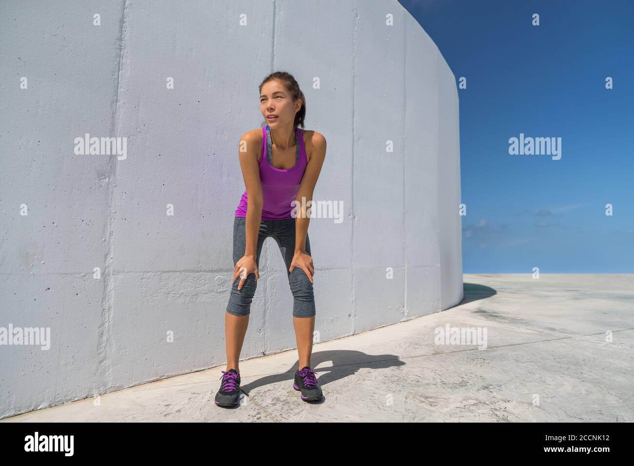 Runner woman tired resting catching breath during cardio workout. Motivation and determination athlete girl ready to run Stock Photo