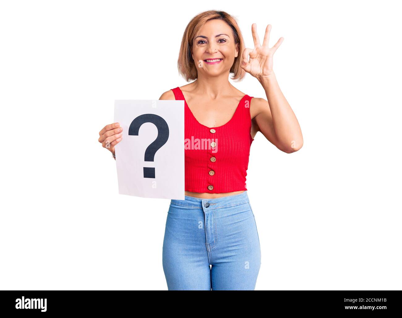 Young blonde woman holding question mark doing ok sign with fingers ...