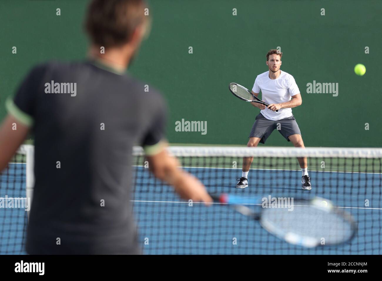 Men sport athletes players playing tennis match together. Two professional tennis players hitting ball on hard outdoor court during game Stock Photo