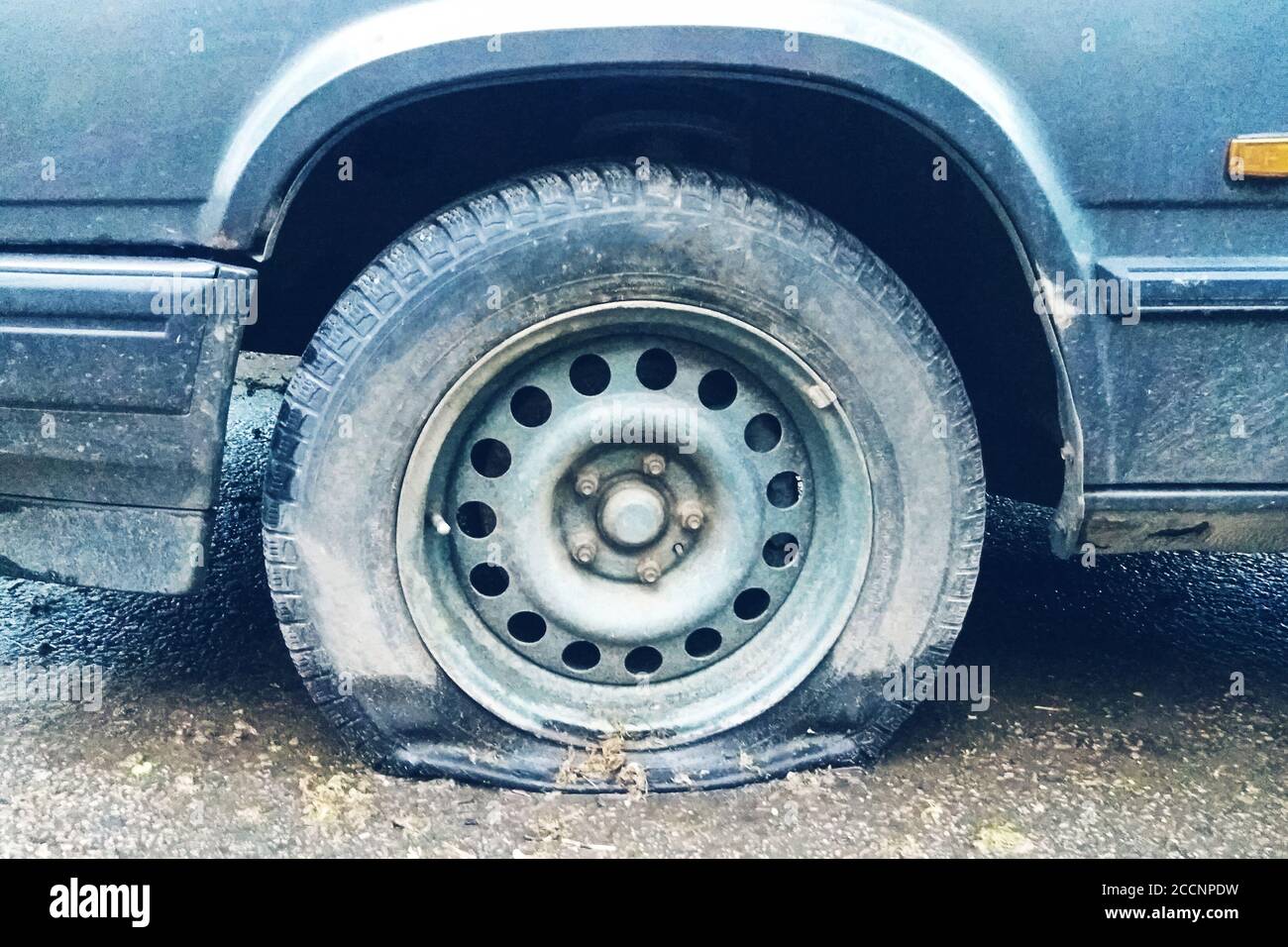 flat tyre of old car outdoors, dirty collapsed tyre close up Stock Photo