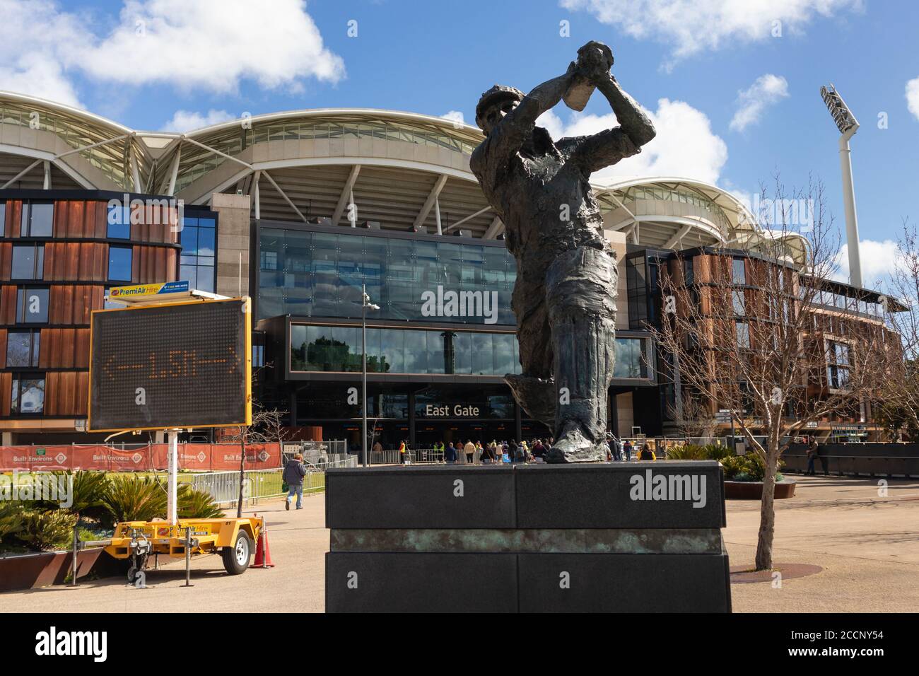Statue of football player in front of the Adelaide Oval. People entering the stadium before a