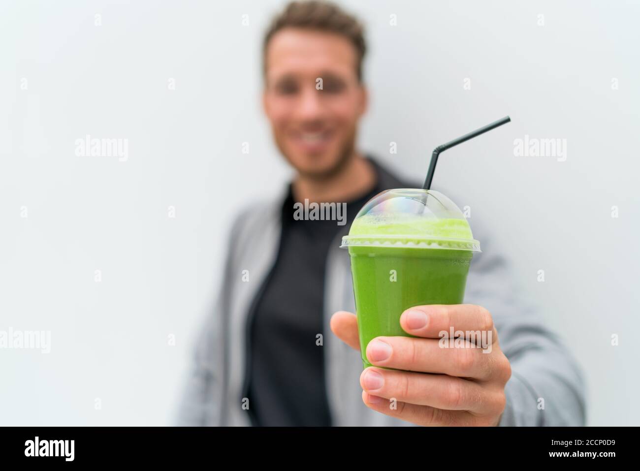 Health man drinking weight loss green smoothie drink. Hand holding plastic cup of vegetable juice, healthy food diet eating lifestyle Stock Photo