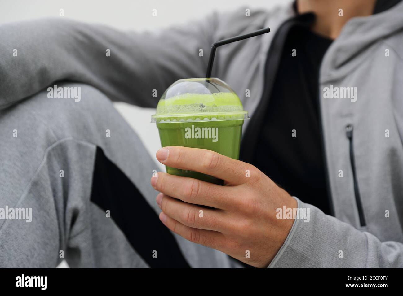 Green smoothie detox man drinking vegetable juice cleanse. Sport athlete holding plastic cup breakfast drink closeup Stock Photo
