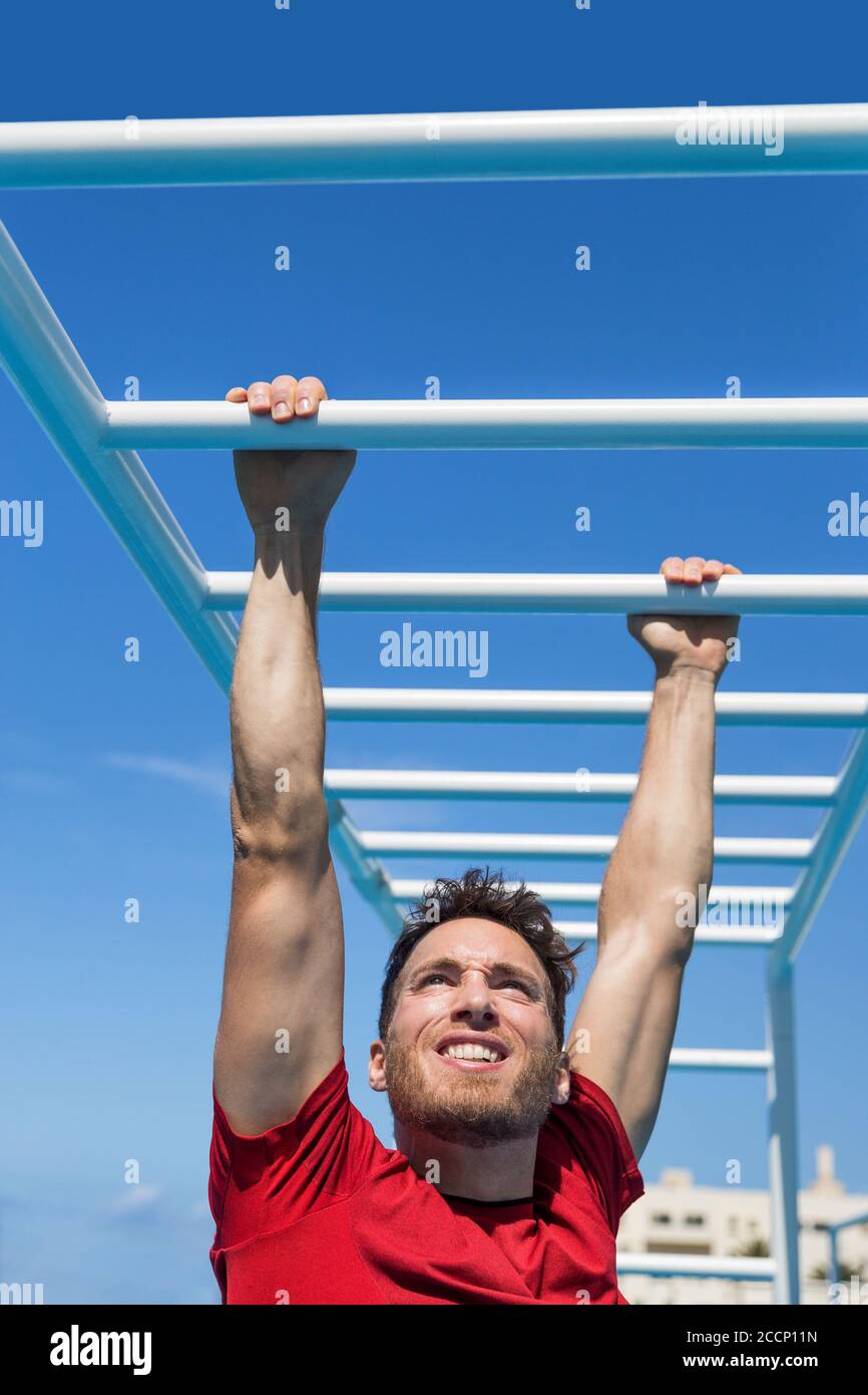 Fitness monkey bars man training arms muscles on jungle gym outdoors in summer. Athlete working out gripping climbing on ladder equipment at sport Stock Photo