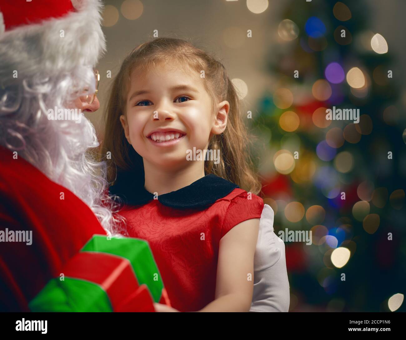 Santa Claus giving a present to a little cute girl Stock Photo - Alamy
