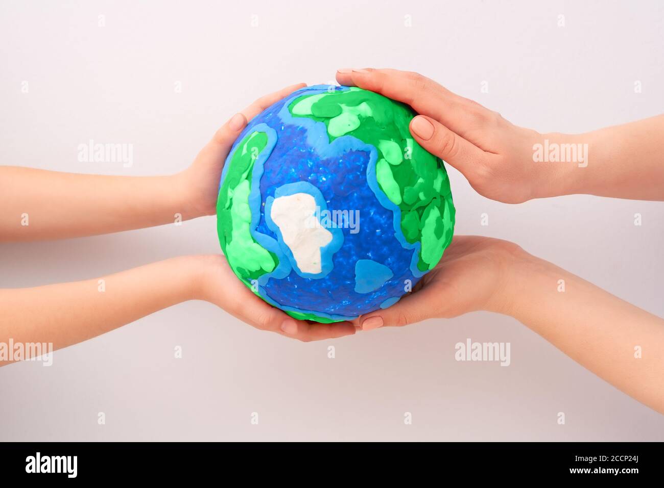 Child and adult holding planet in hands against white background. Earth ...