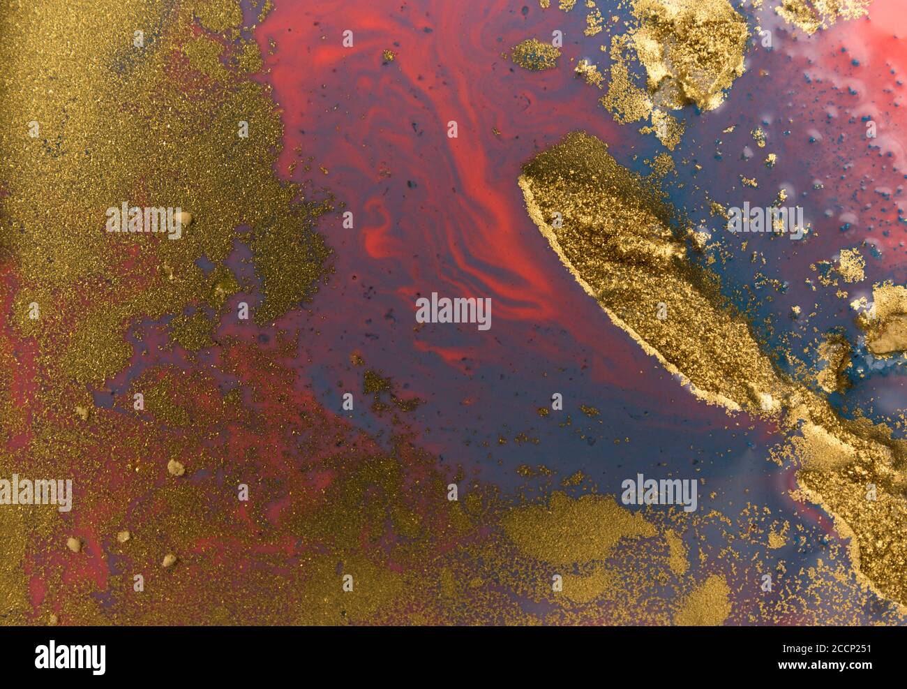 Piles of gold sequins on blue liquid ink background. Abstract pattern