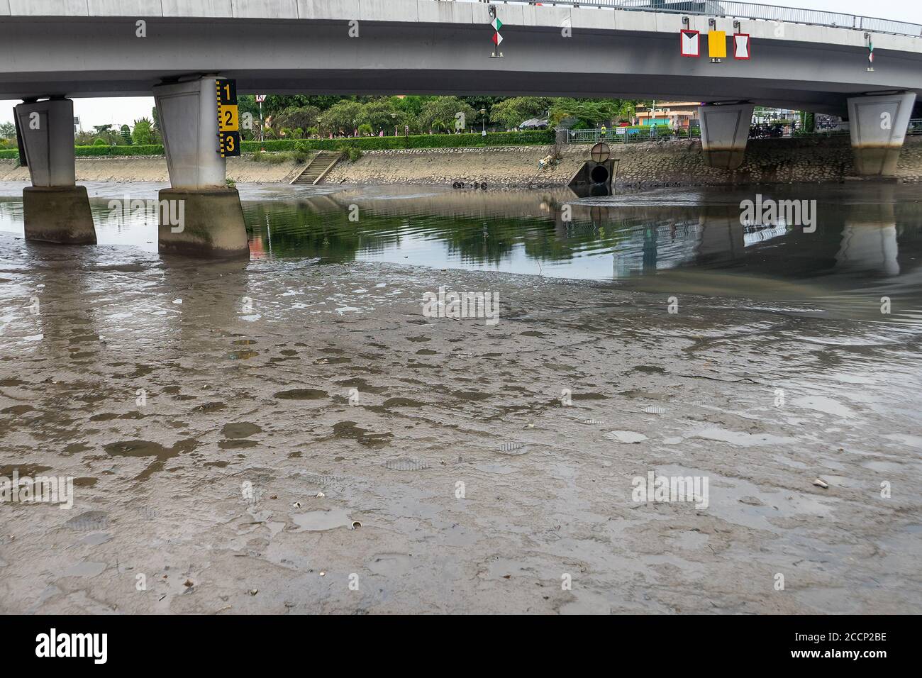 Dry river bottom is visible due to lowering of the water level in Saigon River. Water level markers on the bridge supports. Summer drought in Ho Chi M Stock Photo