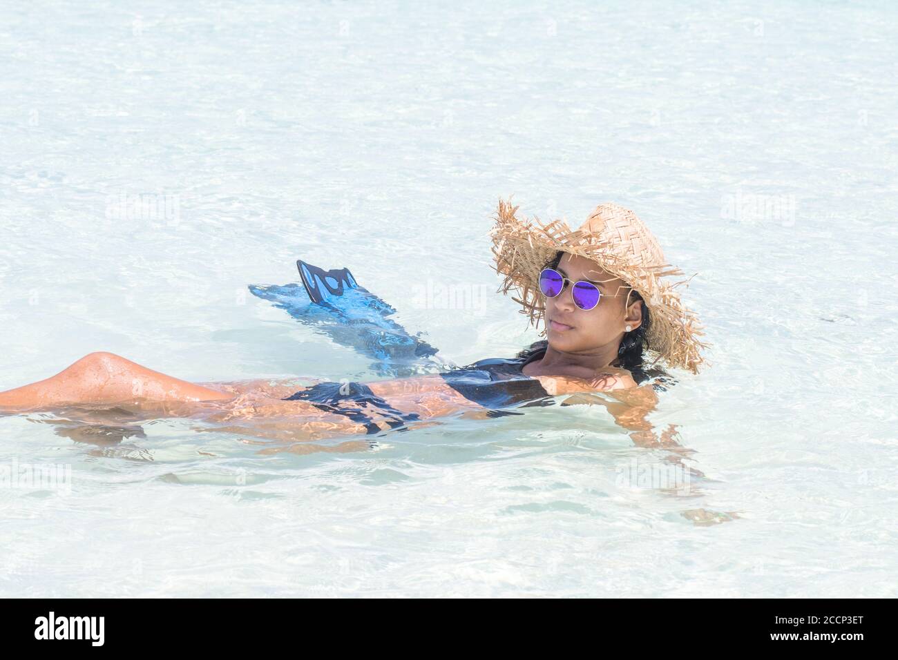 Hispanic woman with hat beach and fins enjoying inside turquoise water in sunny day at caribbean beach Stock Photo