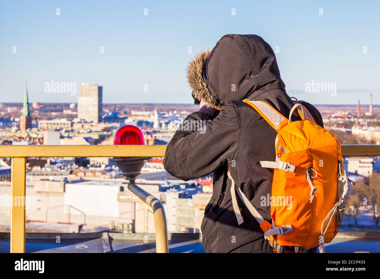 Photographer with big bag taking picture landmark the ancient european city from a high view point. Latvian Academy of Sciences. Sunny winter day Stock Photo