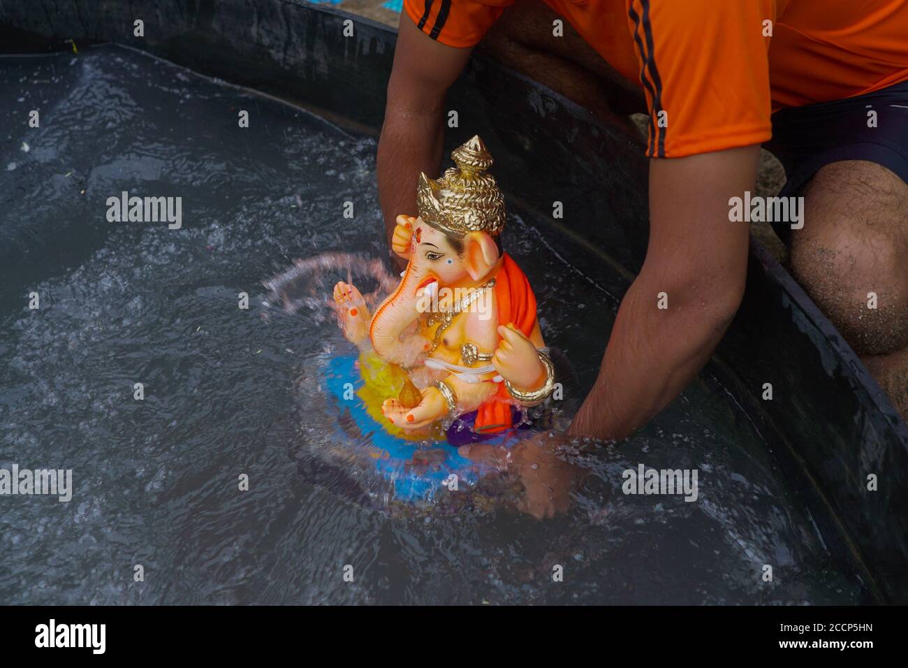 Ganesh idol immersion in covid 19 pandemic restrictions. Ganpati Visarjan In Man Made pond People With Mask -Mumbai, Maharashtra / India. Stock Photo