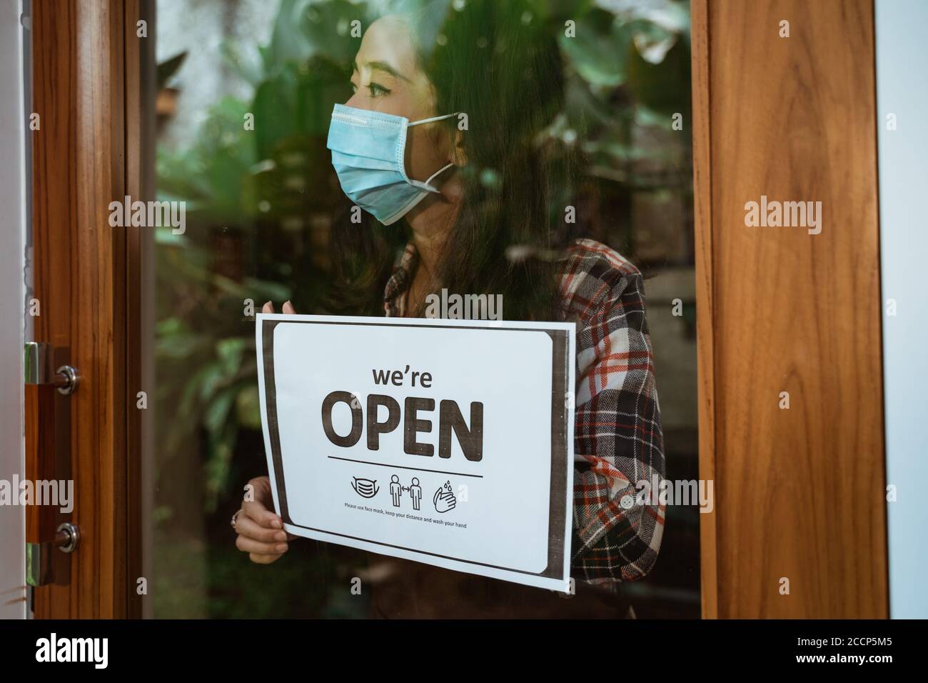 asian woman with open sign in her shop during covid-19 pandemic. new normal life keep your distance sign Stock Photo