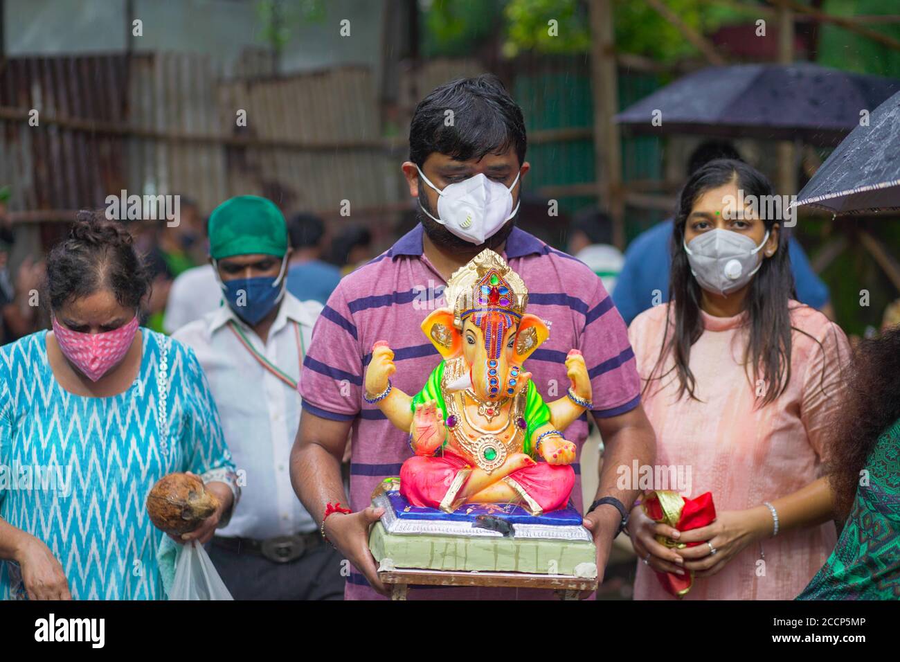 Ganesh idol immersion in covid 19 pandemic restrictions. Ganpati Visarjan In Man Made pond People With Mask -Mumbai, Maharashtra / India. Stock Photo