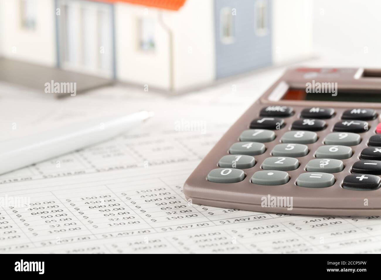 Pocket calculator with pen on financial analysis sheets with house model, real estate investment or poroperty costs concept, selective focus Stock Photo