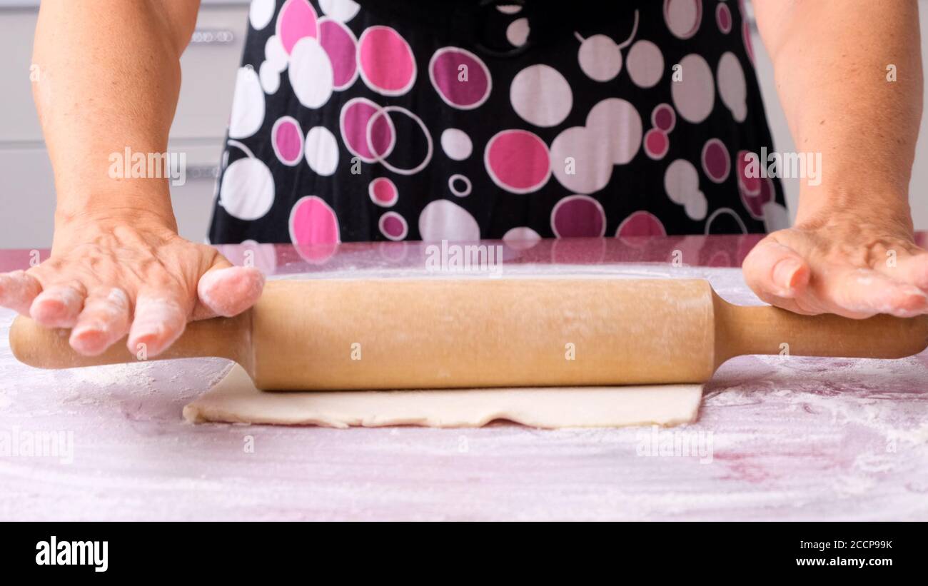 Cooking dough with a rolling pin on the table. Working at the bakery ...