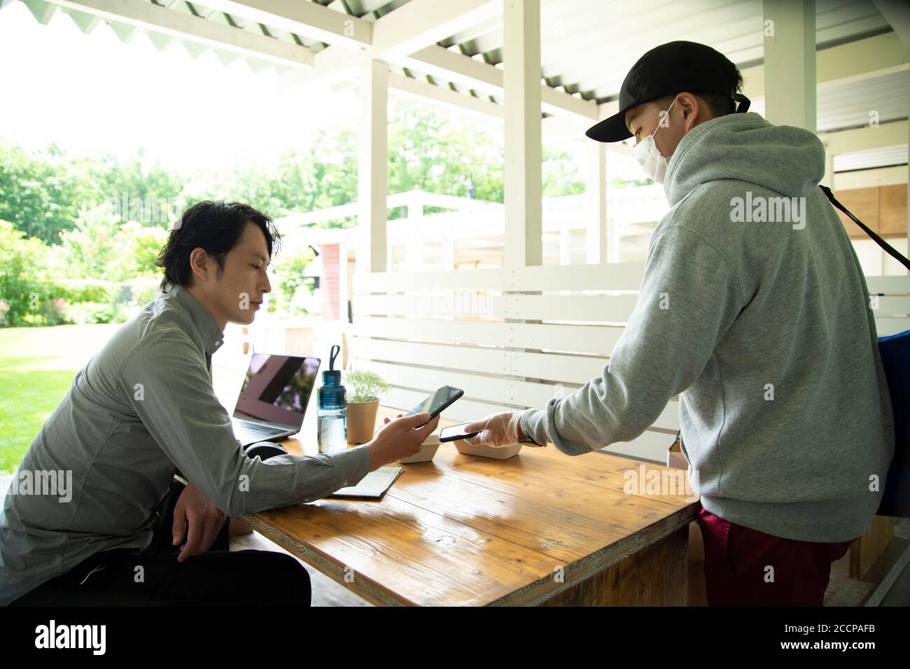 Mature Man and Delivery Person Using E-Payment Stock Photo